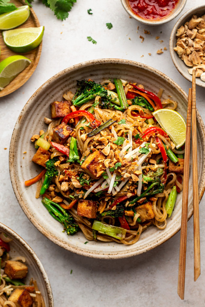 A plate of pad thai with chop sticks.