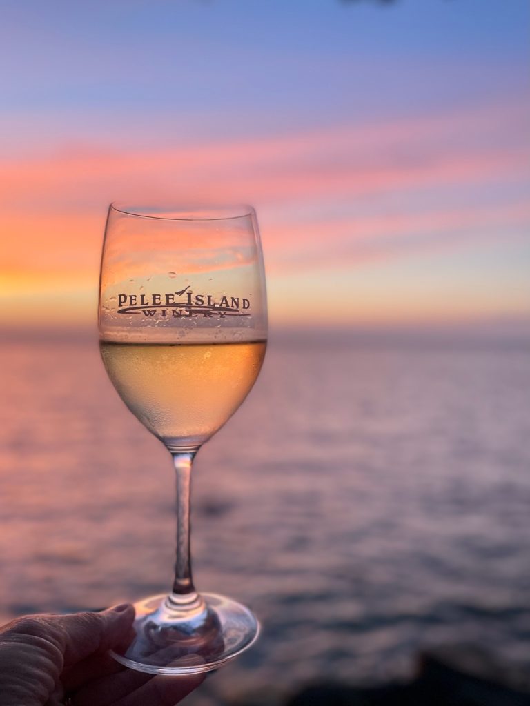 Pelee Island Winery glass of Vinedressers Chardonnay VQA Ontario sustainable wine lighting the way from vine to wine to glass over Lake Erie on Pelee Island Ontario