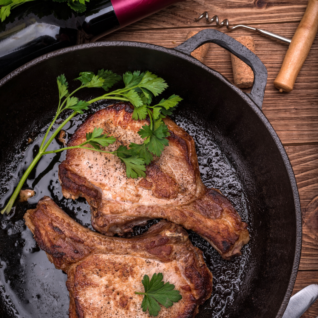 BBQ porkchops in a cast iron pan with a bottle of red wine 