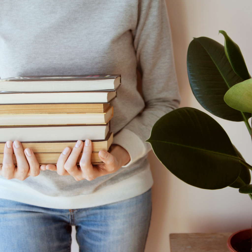 Person holding a stack of books.